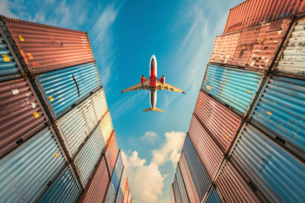 Cargo plane flying over stacked containers